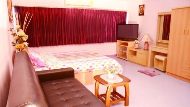 A bedroom with a bed, a sofa, a TV, a desk, and a wardrobe. - Donmuang - Impact Condo Service (Pak Kret)
