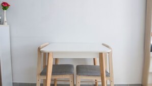 A small wooden table with two chairs, a white wall, and a tiled floor. - Muangthong Inn (Pak Kret)
