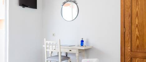 Un dormitorio con cama, escritorio, silla, televisor y puerta de madera.