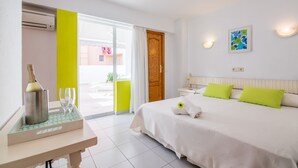 A hotel room with a bed, a bedside table with a bottle and glasses, a window with a view, and a door leading to an outdoor area. - Garau Petit Hotel (Palma de Mallorca)