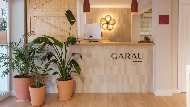 A reception desk with the name "GARAU PETIT HOTEL" and three potted plants. - Garau Petit Hotel (Palma de Mallorca)