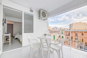 A balcony with white plastic chairs, a small table, and a potted plant. - Garau Petit Hotel (Palma de Mallorca)