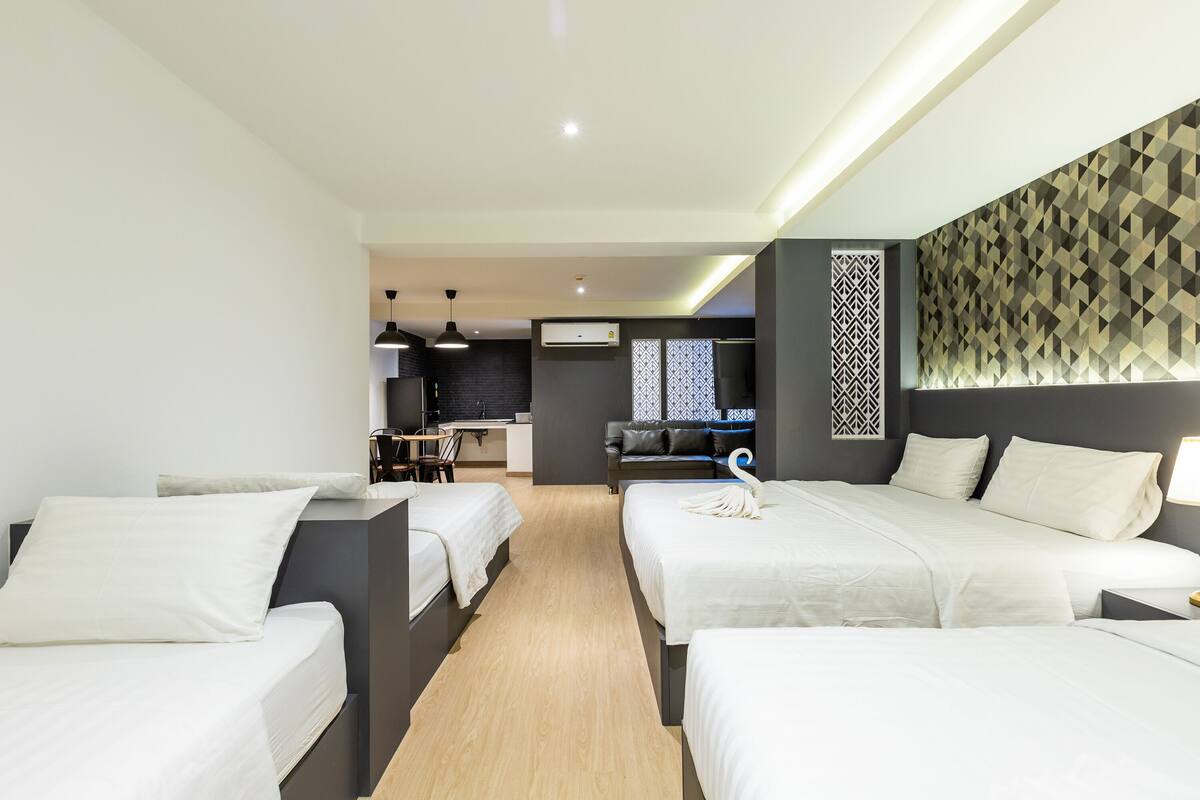 A hotel room with two beds, a kitchenette, a dining area, and a patterned wall.