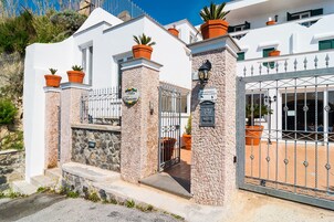 Un edificio blanco con pilares de piedra, una entrada porticada y plantas en macetas.