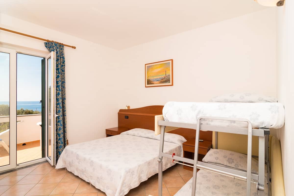 A bedroom with a bunk bed, a single bed, a wooden nightstand, and a painting on the wall.