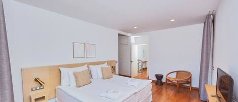 Une chambre d’hôtel avec un lit double, des tables de chevet, une télévision et un plancher en bois.