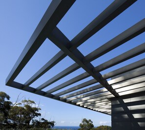 Een modern architectonisch gebouw met een reeks horizontale balken die een patroon vormen tegen een heldere blauwe lucht.