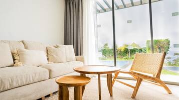 Una sala de estar moderna con un sofá, una mesa redonda de madera y una silla de mimbre.