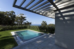 A modern outdoor pool area with a clear view of the ocean, surrounded by lush greenery and a pergola structure. - Coral Villas La Quinta (Santa Ursula)