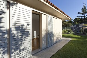 A modern house with a large sliding door, a small porch, and a well-maintained lawn.