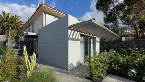 Una casa moderna amb teulada plana, escala de pedra i jardí amb cactus i plantes de flors.