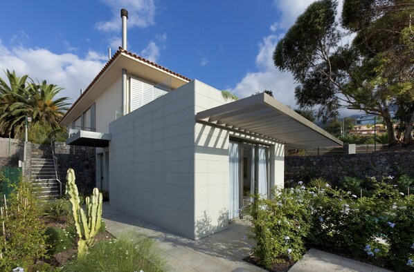A modern house with a flat roof, a stone staircase, and a garden with cacti and flowering plants. - Coral Villas La Quinta (Santa Ursula)