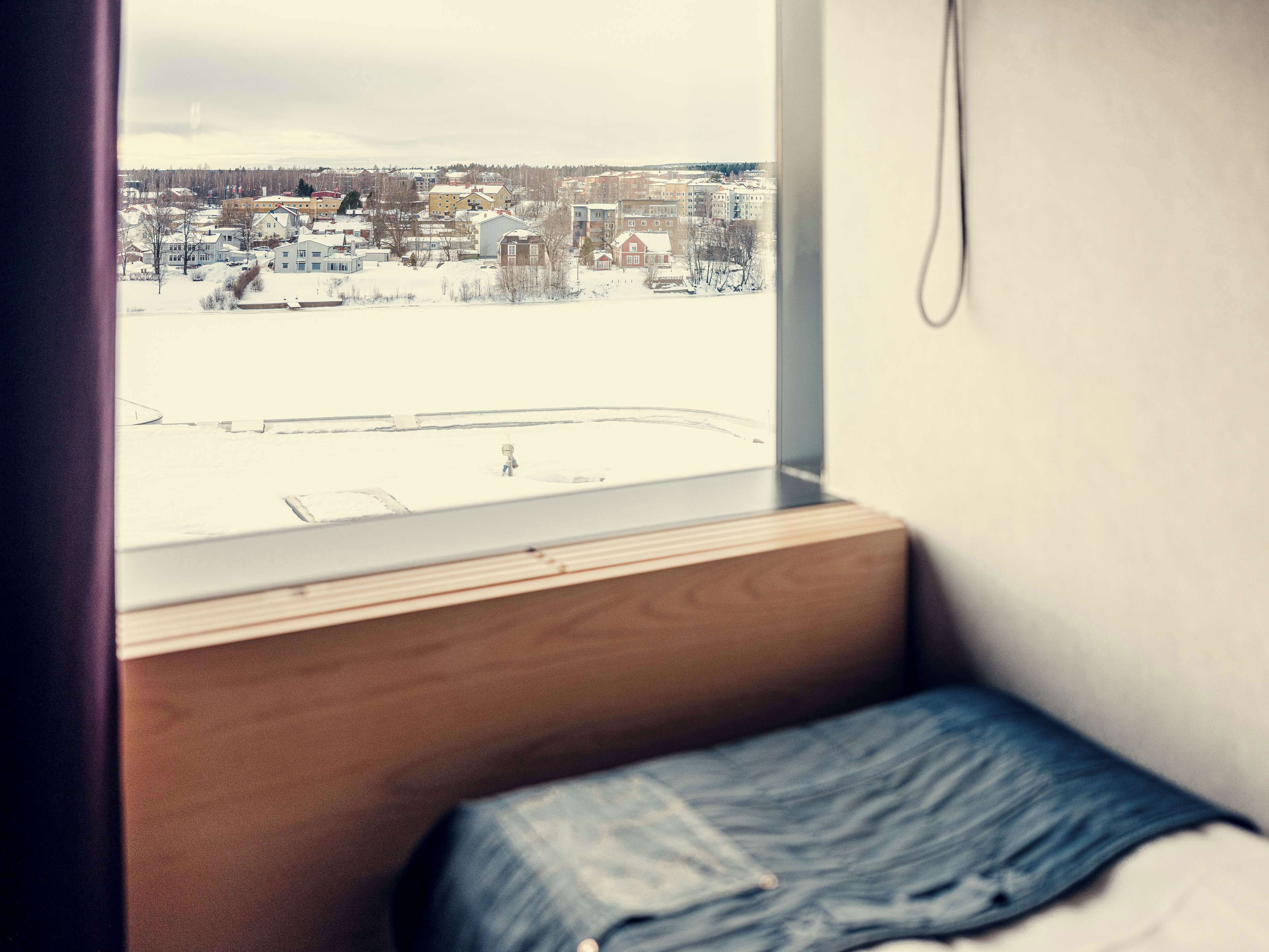 A bedroom with a window overlooking a snowy landscape.