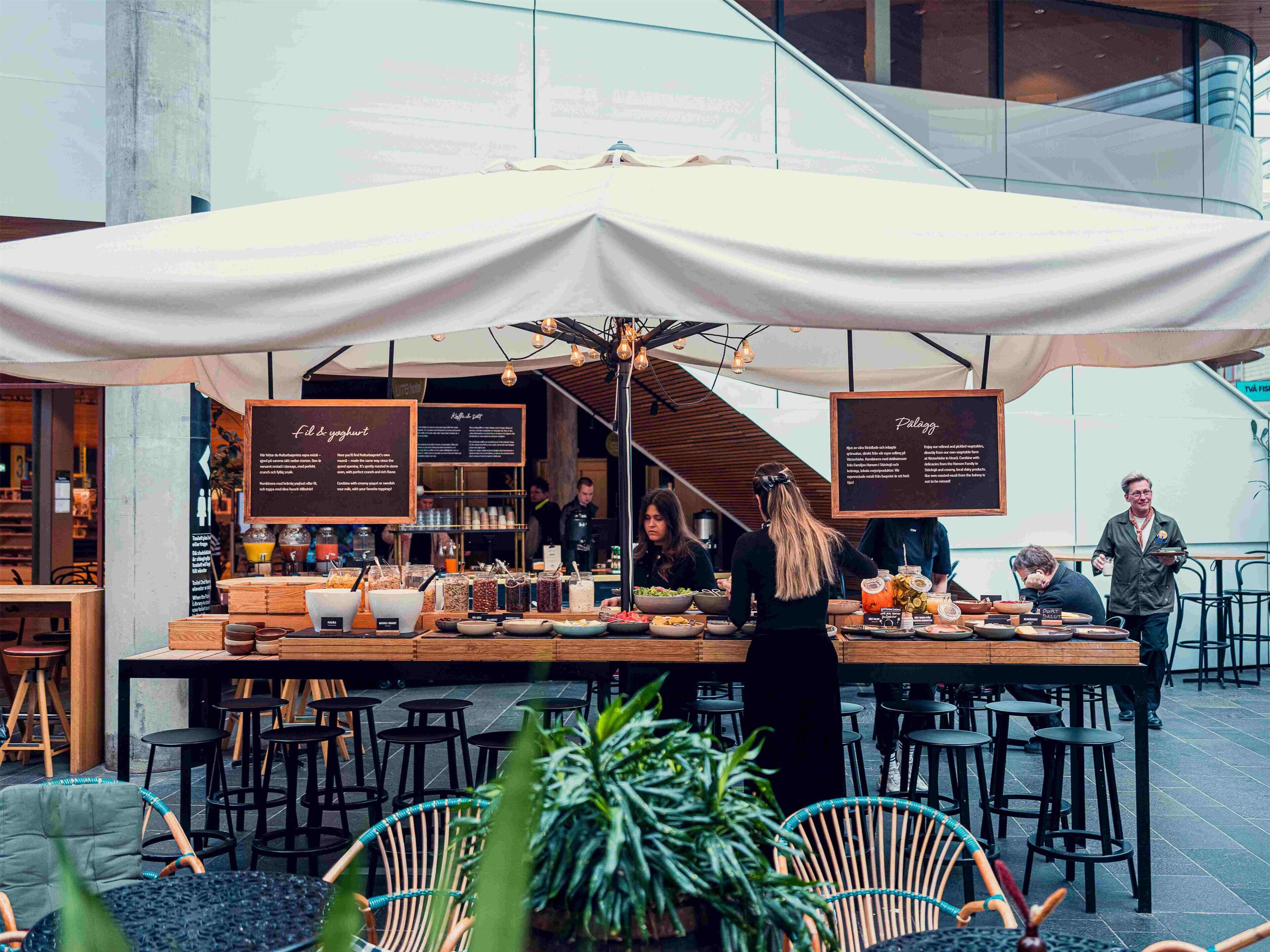 An outdoor dining area with a covered table, menu boards, and chairs.