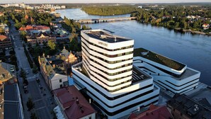 Un hotel moderno dall'architettura unica e sinuosa, affacciato su un fiume con un ponte sullo sfondo.