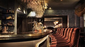 A bar area with a long counter, plush red seating, and a chandelier. - U&Me, BW Signature Collection (Umea)