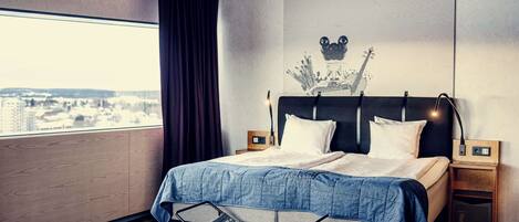 A modern hotel room with a large bed, a view of the city, and a unique ceiling design.