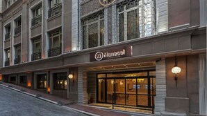 Un hotel con fachada moderna, un logotipo destacado sobre la entrada y un área de acceso bien iluminada.