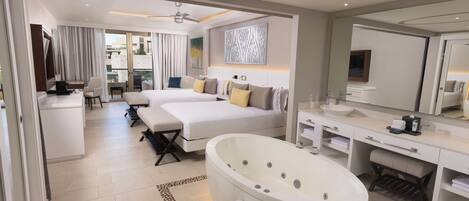 A modern hotel room with a large bed, a separate desk, a walk-in closet, a large bathtub, and a balcony with curtains.