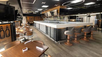 A modern bar area with a central island, bar stools, and a seating area with tables and chairs.