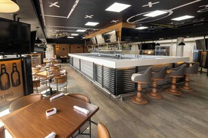 A modern bar area with a central island, bar stools, and a seating area with tables and chairs.