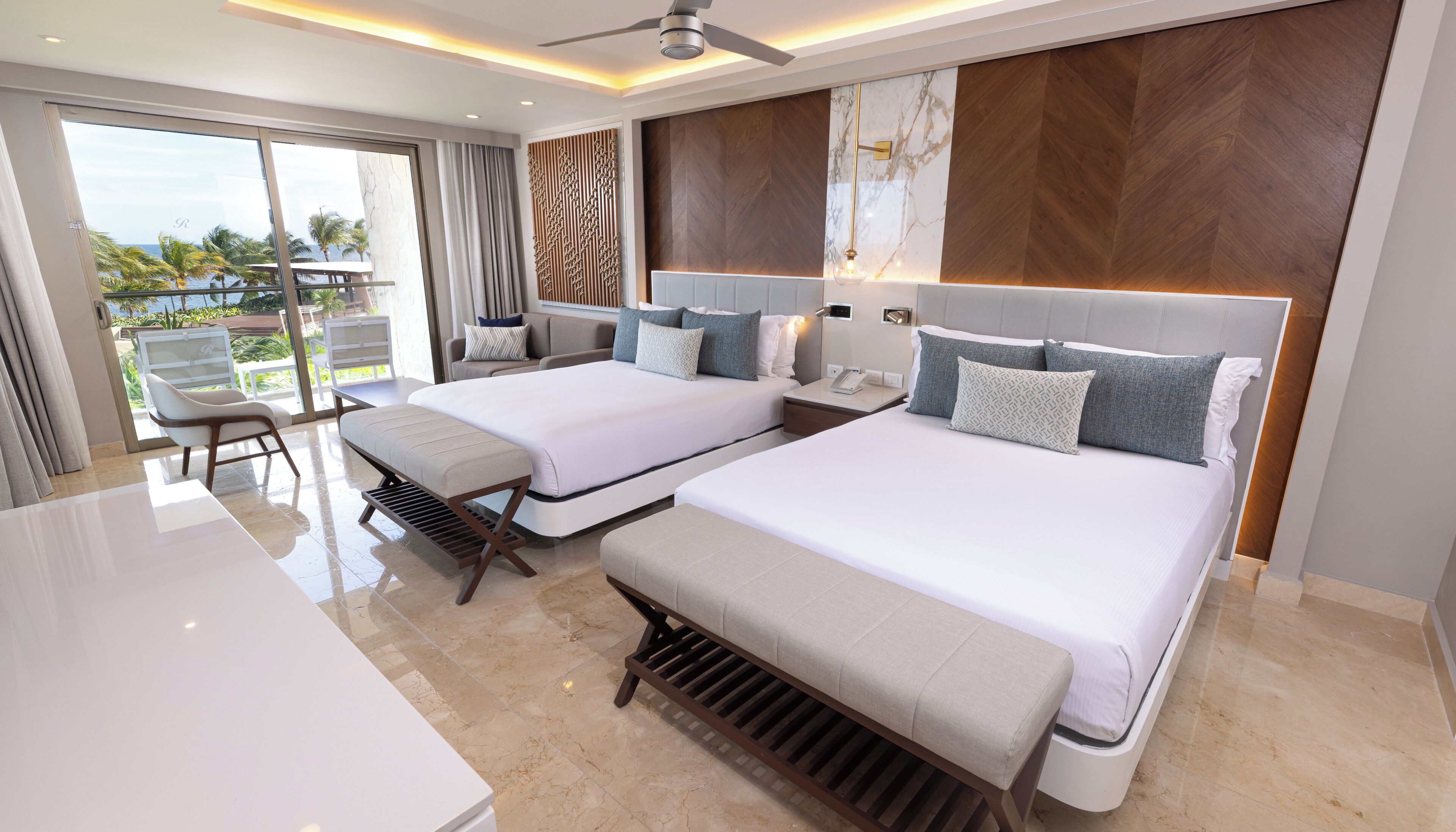 Habitación de hotel con dos camas, un balcón y vista al océano.
