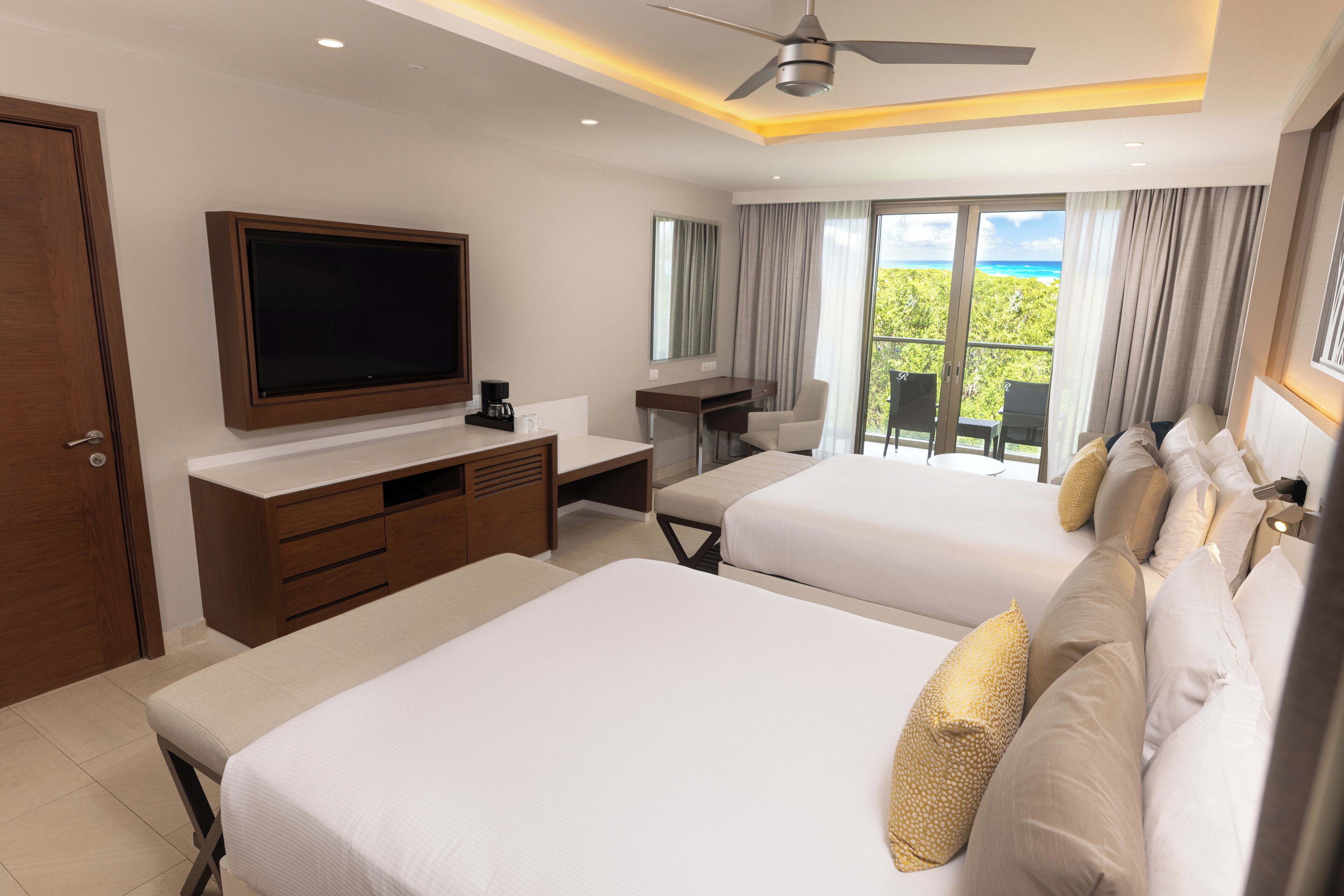 Ein Hotelzimmer mit zwei Betten, einem Schreibtisch, einem Fernseher und einem Balkon mit Blick.