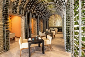 A wine cellar with rows of wine bottles, tables, and chairs.