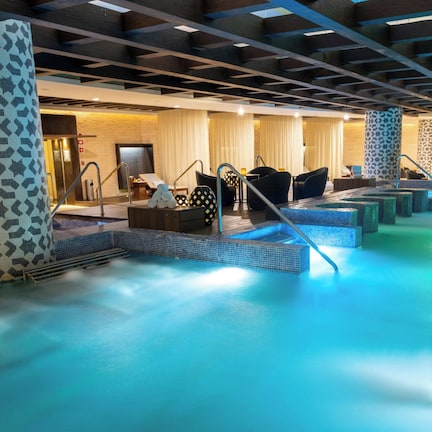 A spa area with a large pool, seating, and a patterned wall.