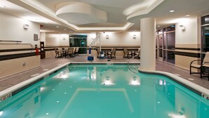 An indoor swimming pool with clear lane markings, a lifeguard stand, and a seating area with chairs and tables. - Hampton Inn & Suites Bellevue Downtown-Seattle (Bellevue)