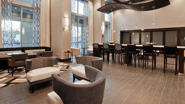 A modern hotel lobby with a dining area, seating arrangements, and large windows. - Hampton Inn & Suites Bellevue Downtown-Seattle (Bellevue)