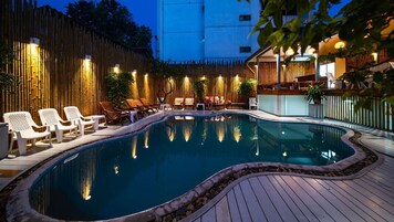 Una piscina al aire libre, sillones reclinables de piscina