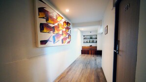 Ein Flur mit Holzboden, einem an der Wand hängenden abstrakten Gemälde, einem Empfangsbereich mit Theke und Regalen sowie einer Tür mit der Aufschrift '101'.