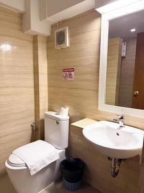 A bathroom with a toilet, sink, and a caution sign on the wall. -  Wild Orchid Villa Bangkok (Bangkok)