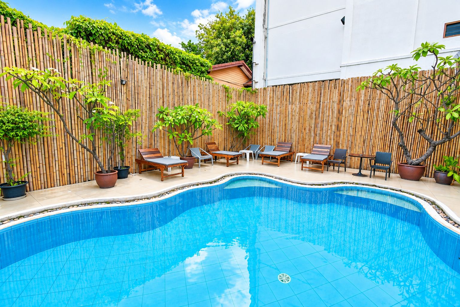 A swimming pool with lounge chairs and potted plants.