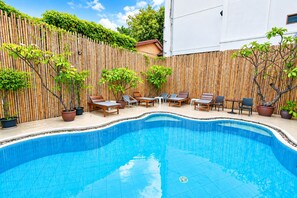A swimming pool with lounge chairs and potted plants. -  Wild Orchid Villa Bangkok (Bangkok)