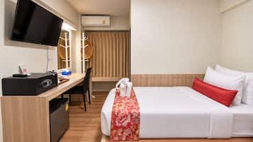 Habitación de hotel con cama, escritorio, televisión y aire acondicionado.