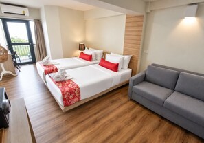 A hotel room with two beds, a grey sofa, wooden flooring, and a balcony with a view. -  Wild Orchid Villa Bangkok (Bangkok)