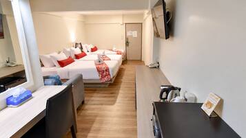 A hotel room with a bed, bedside table, chair, desk, and a TV mounted on the wall.