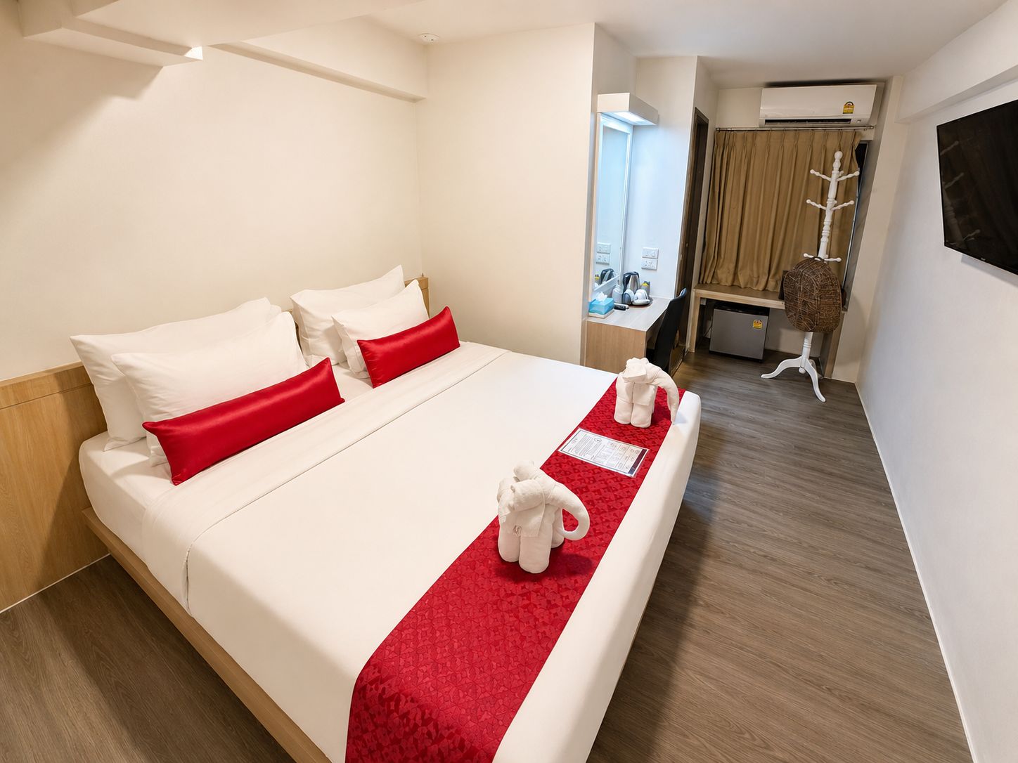 Habitación de hotel con cama, escritorio, silla, equipo de aire acondicionado y televisor.