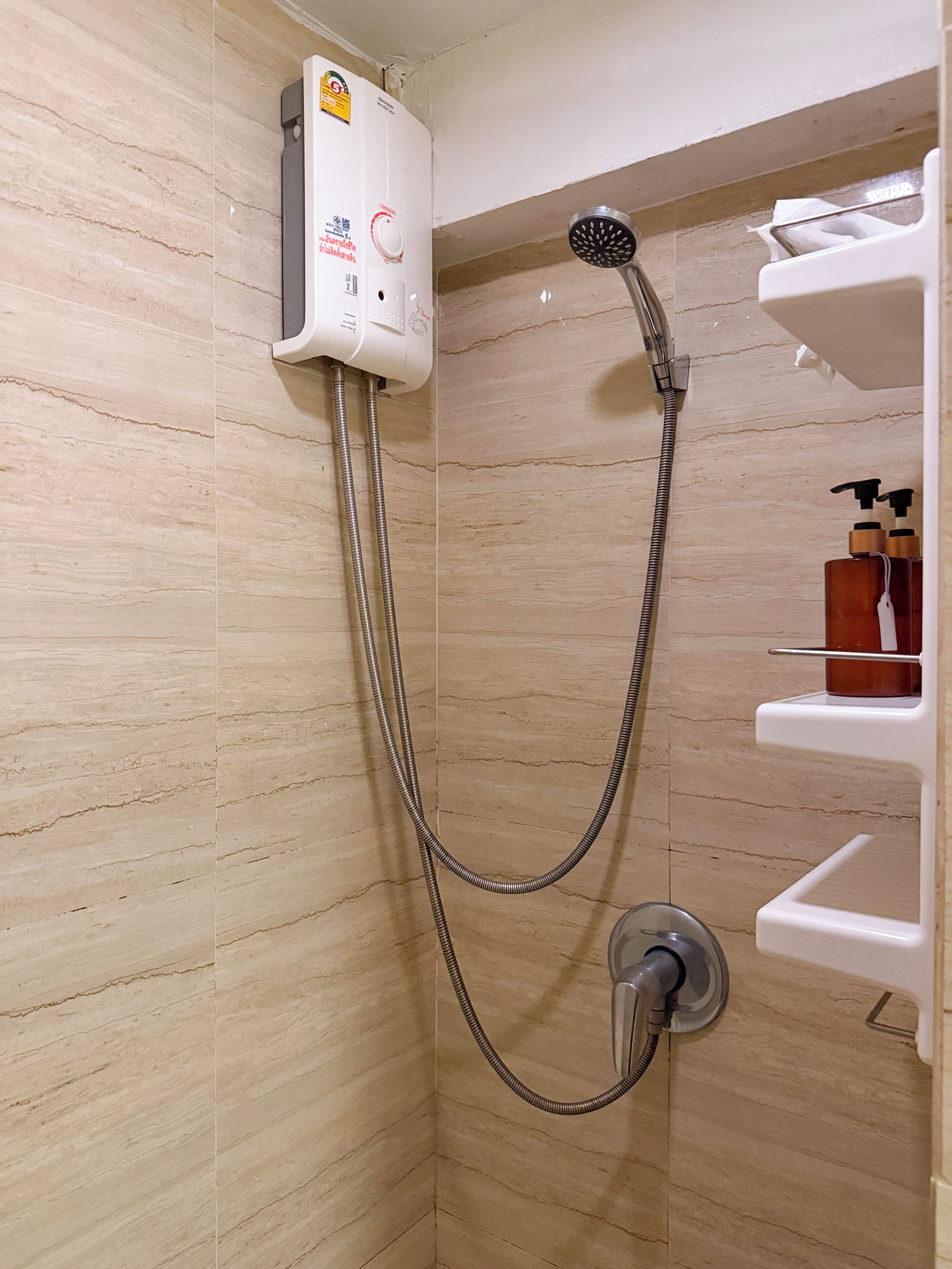 A shower with a handheld showerhead and a wall-mounted control panel.