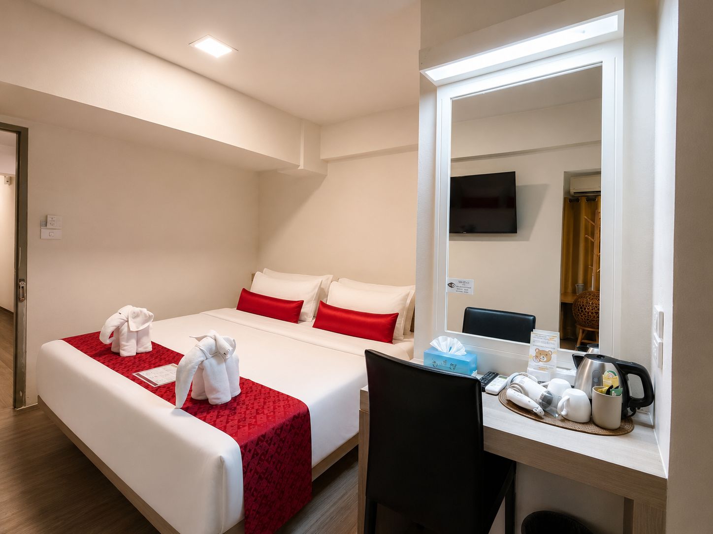 Ein Hotelzimmer mit Bett, Schreibtisch, Stuhl, Fernseher und Spiegel.