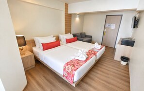 A hotel room with two beds, a desk, a TV, and a trash bin. -  Wild Orchid Villa Bangkok (Bangkok)