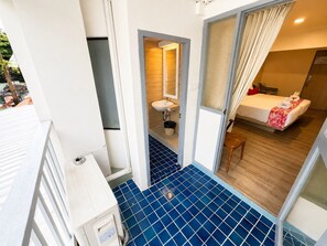 A hotel room with a bed, a bathroom, and a view of the outside. -  Wild Orchid Villa Bangkok (Bangkok)