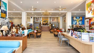 A hotel lobby with a reception desk, seating area, and artwork on the walls.