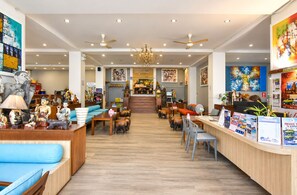 A hotel lobby with a reception desk, seating area, and artwork on the walls. -  Wild Orchid Villa Bangkok (Bangkok)