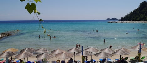 Een privéstrand, wit zand, ligstoelen aan het strand, parasols