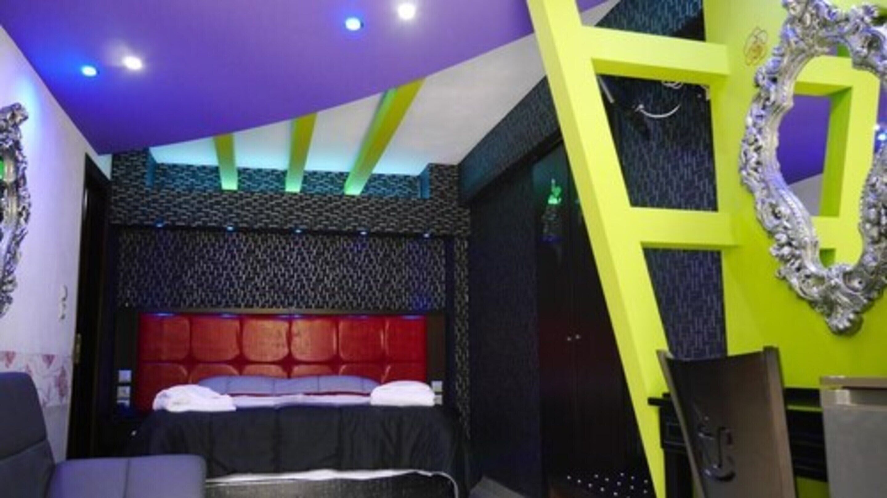 Ein modernes Schlafzimmer mit einem gemusterten Kopfteil, einem Bett mit roter Bettwäsche und einem einzigartigen geometrischen Wanddesign.