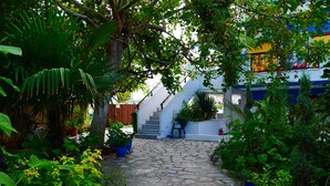 A stone pathway leading to a staircase surrounded by lush greenery and potted plants. - Blue Sea Beach Resort (Thasos)