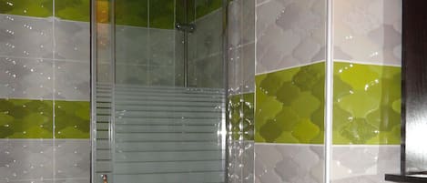 A bathroom with a glass shower enclosure, a toilet, and a sink.